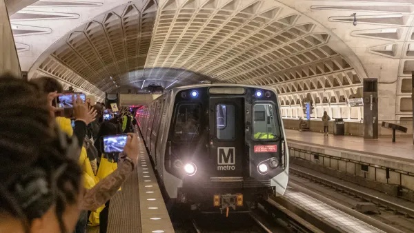 Metrorail train pulling into newly opened subterranean station in Washington, D.C. with crowd on platform taking photos.